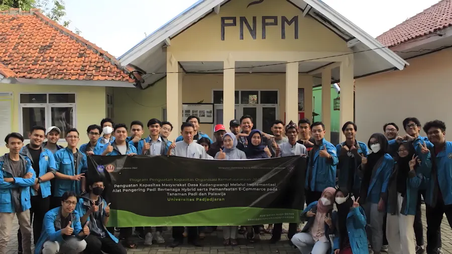 Padiku project team and Kudangwangi community members gathered in front of a program banner.