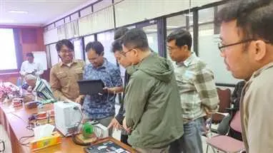 Project team reviewing a hardware setup around a table in a meeting room.