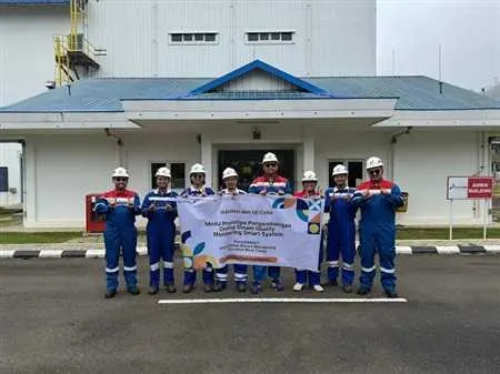 Geothermal project team in PPE holding a Perta-SMART banner outside a facility.